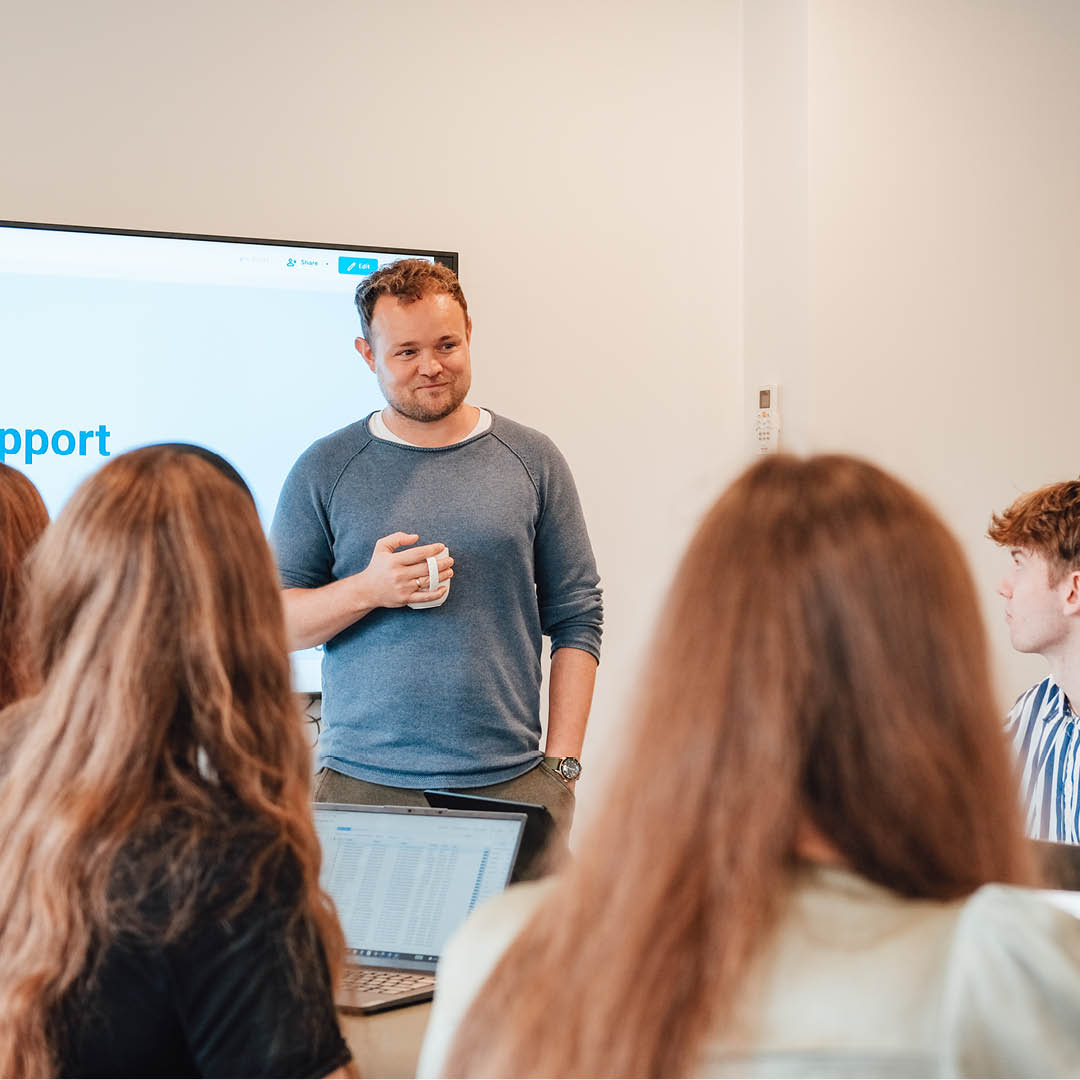 Geniads' grundlægger Jesper Balleby står foran skærm foran Geniads teamet.